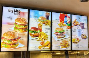 Digital Signage Point-of-Sale Videowand in Form von digitalen Menütafeln in McDonalds. Diese digitale Beschilderung oder Video Wall wird unterstützt mit MagicInfo zur Remotesteuerung und -management.